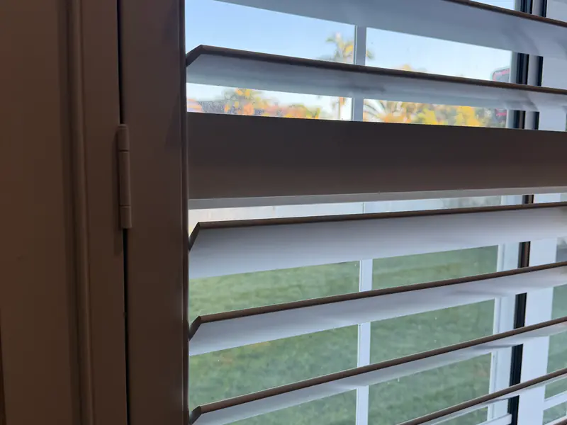 Close-up of plantation shutter louvres tilted open, showing the blade edges and the gaps between them